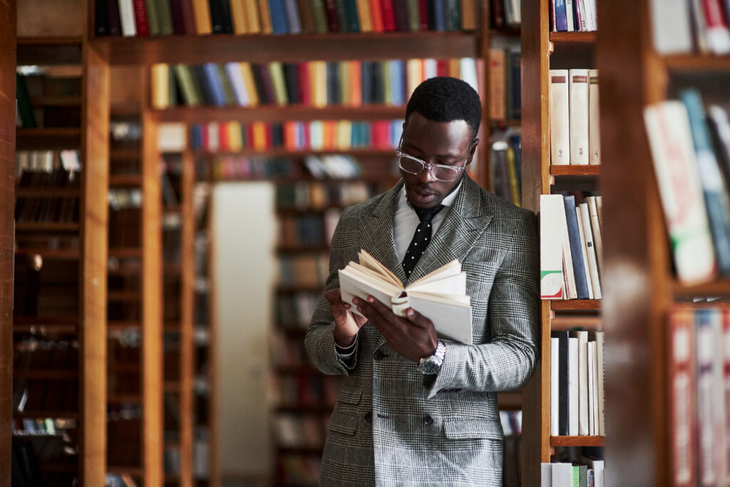 An African American man in a business suit standing in a library in the reading room